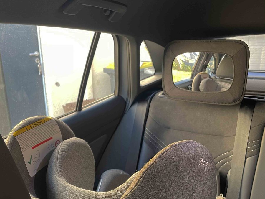 Autospiegel voor baby bevestigd aan de achterste hoofdsteun tegenover een achterwaarts gericht autostoeltje